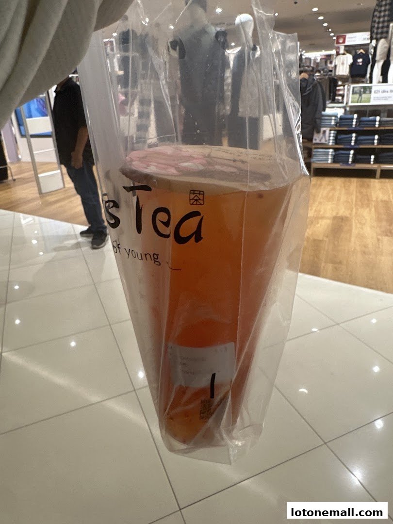A person holds a plastic bag containing a large iced tea from Miss Tea.