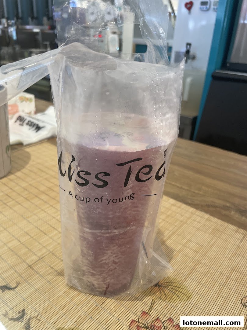 A close-up of a purple beverage in a plastic cup with the "Miss Tea" logo.