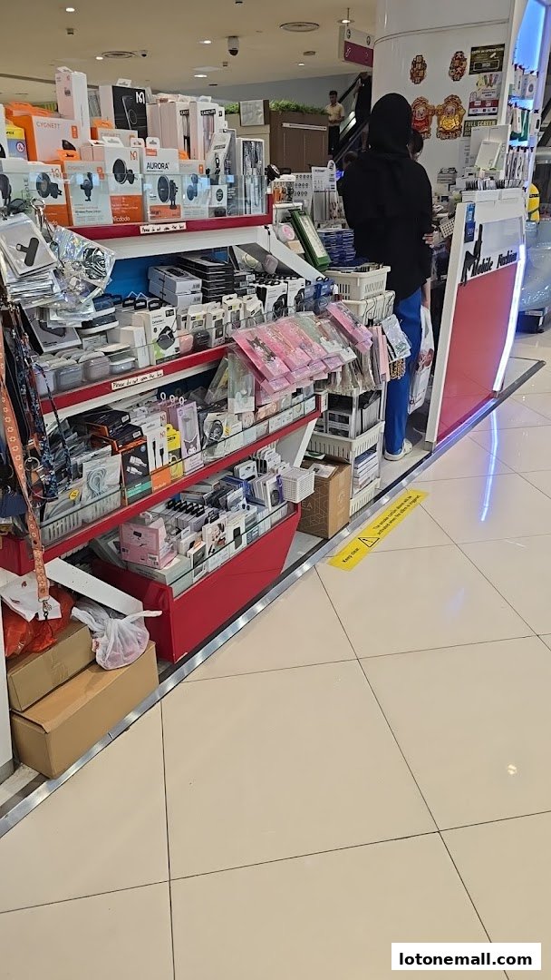 A retail display filled with mobile accessories and electronics, with a staff member behind the counter.
