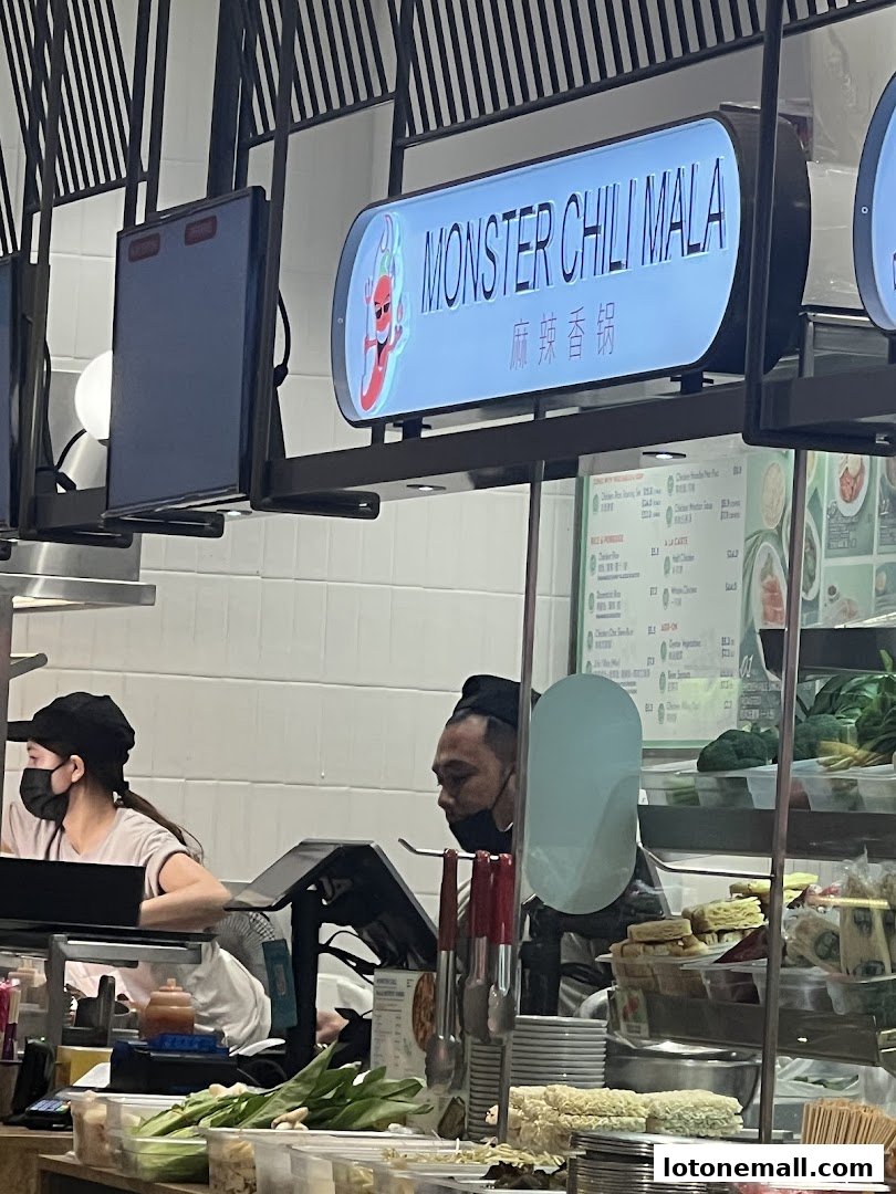 A food stall with a "Monster Chili Mala" sign and staff preparing food.