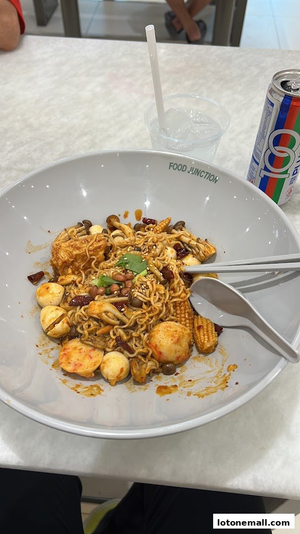 A large bowl of spicy noodles with various toppings and a drink.
