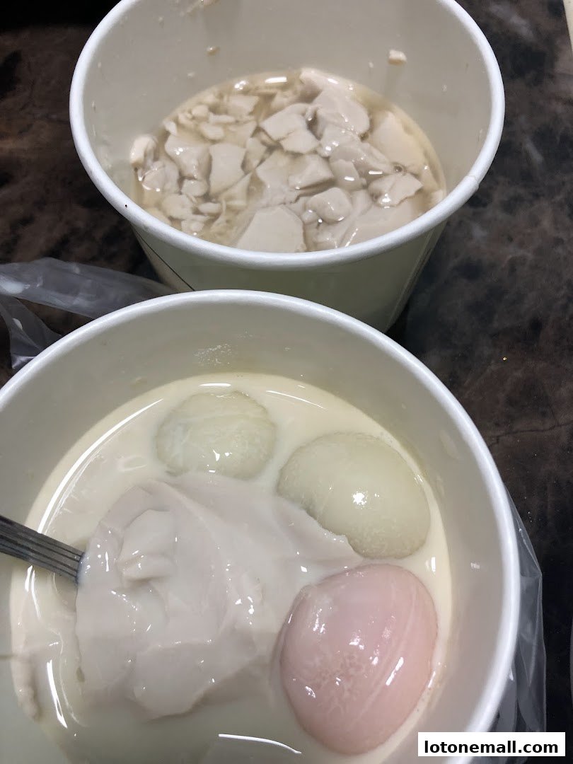 Two cups of traditional Asian dessert, likely douhua, with toppings.