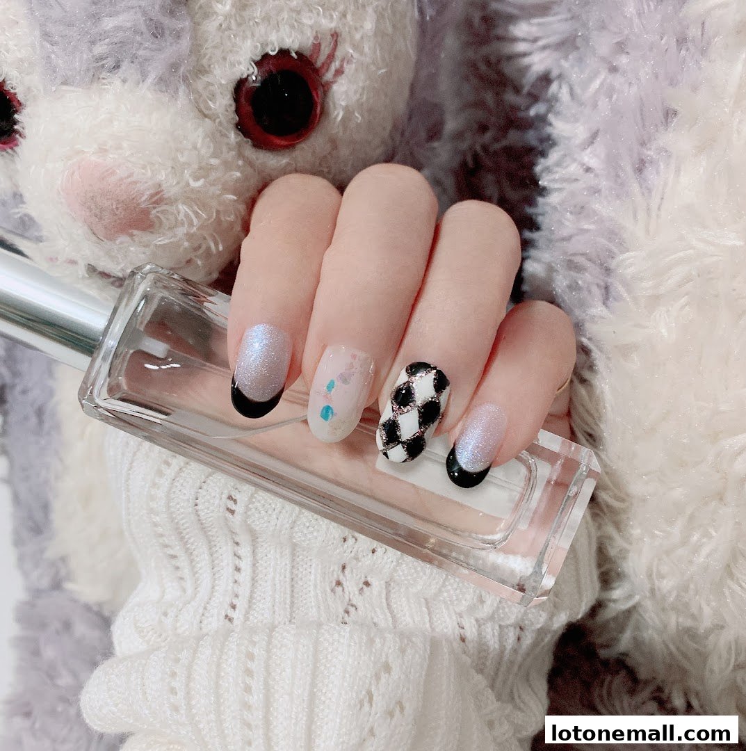 A hand with stylish, decorated nails holding a clear perfume bottle.