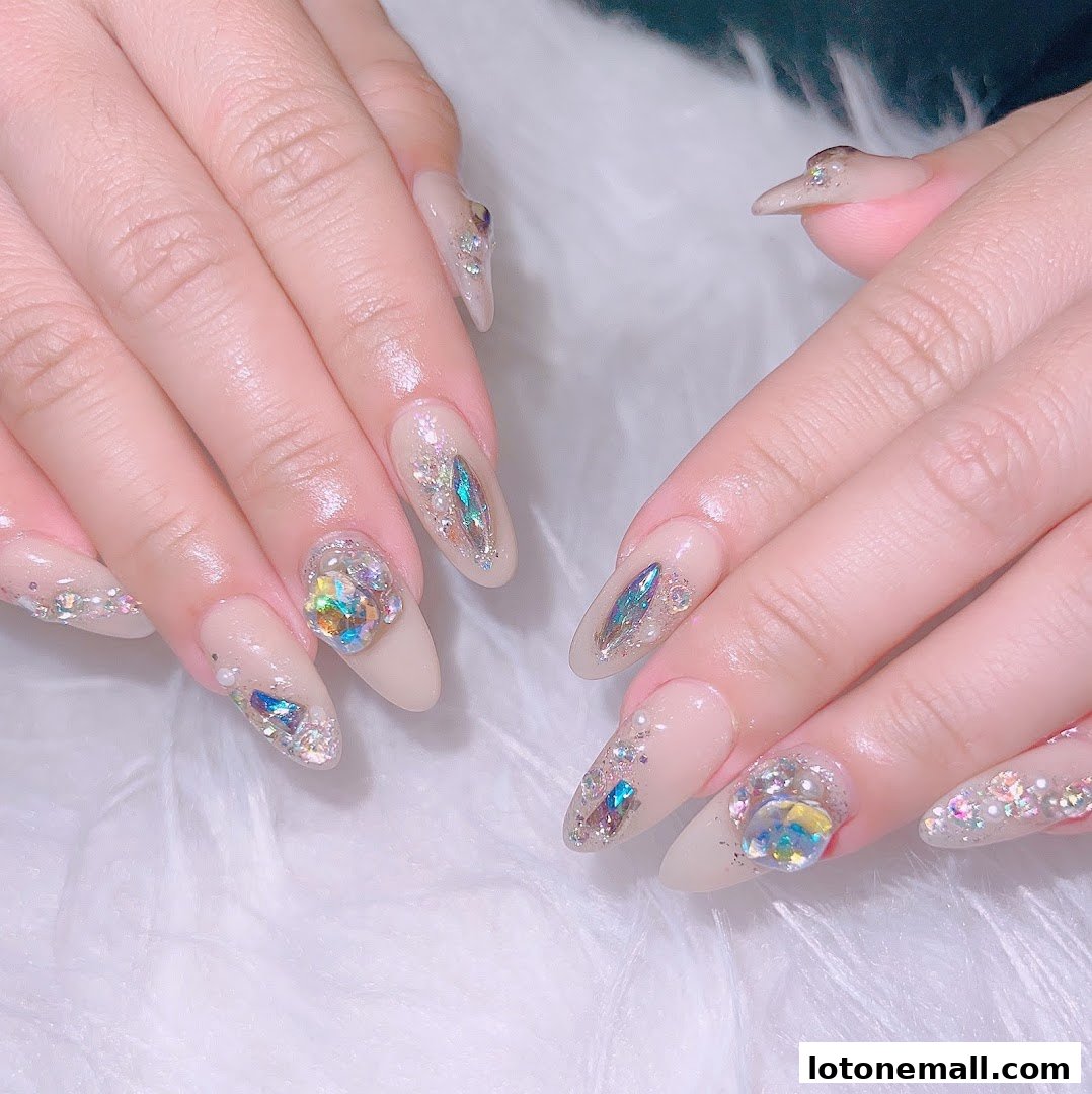 Close-up of hands with elaborate, gem-encrusted almond-shaped nails.