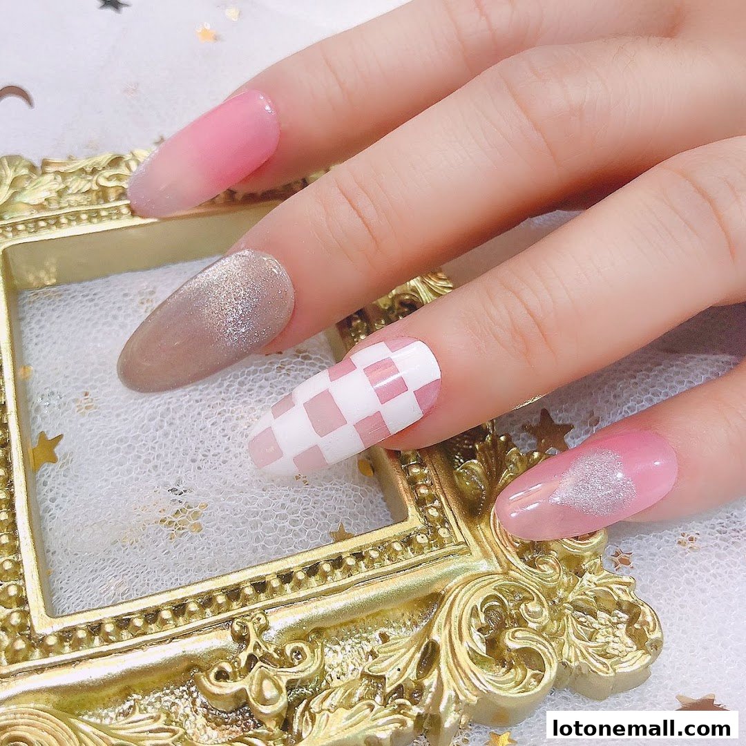Close-up of a hand with beautifully designed nails, featuring pink ombre, glitter, and a checkered pattern.