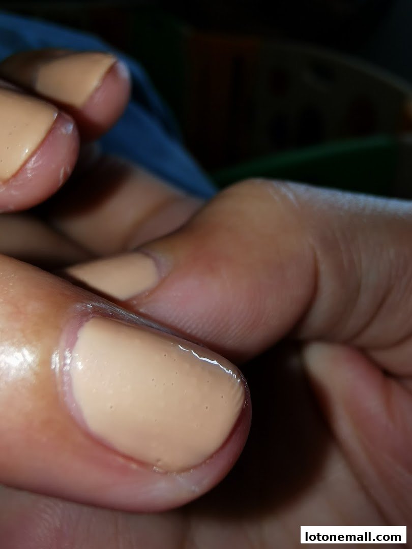 Close-up of a hand with neatly painted nude-colored fingernails.