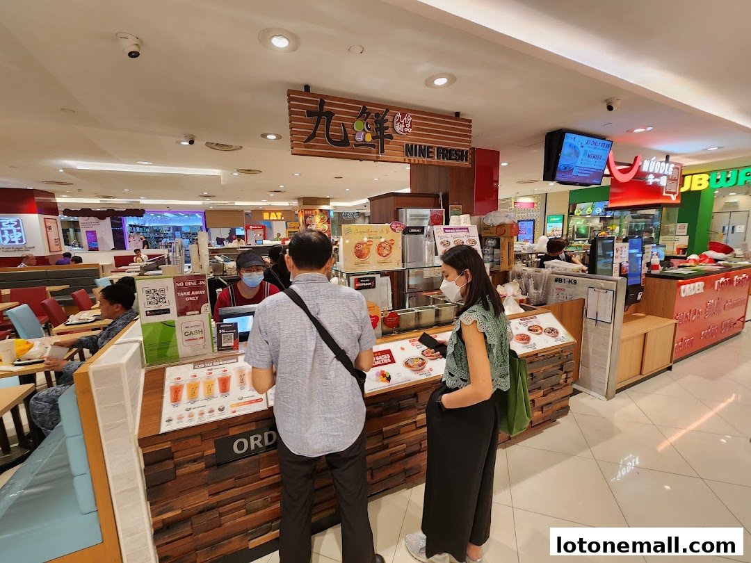 Customers ordering at a Nine Fresh Desserts counter in a mall food court.