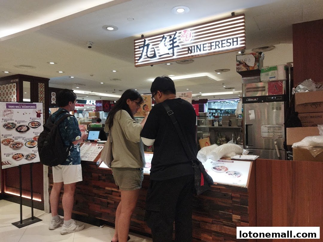 Customers ordering at a Nine Fresh Desserts Taiwan counter with a menu board.