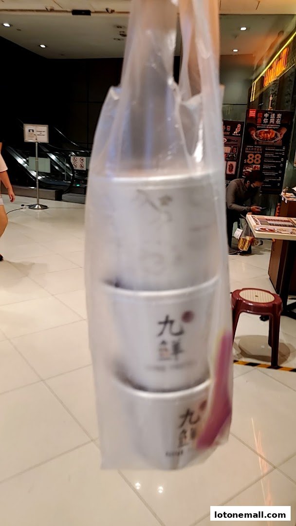 A plastic bag holding three white dessert cups with Chinese characters and English text.