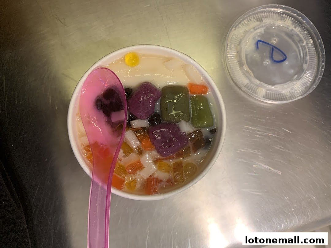 A bowl of Taiwanese dessert with various toppings and a pink spoon.