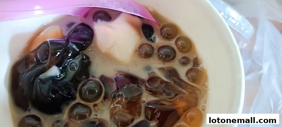 A close-up of a refreshing dessert with various toppings and a pink spoon.