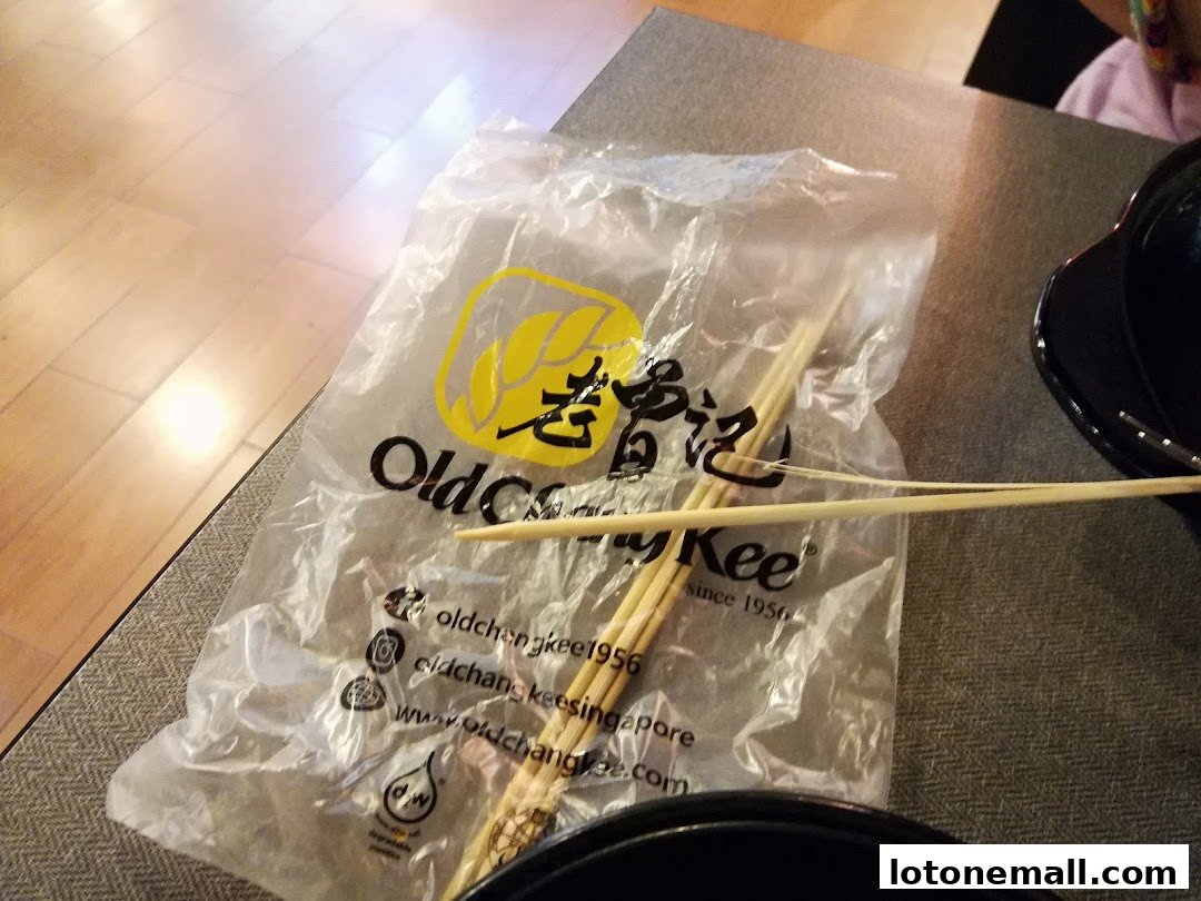 A plastic bag with chopsticks from Old Chang Kee on a table.