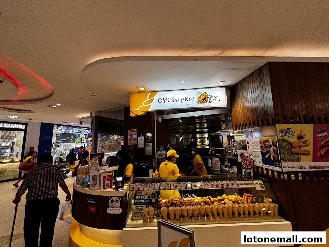A busy Old Chang Kee shop with staff serving customers and a display of fried snacks.