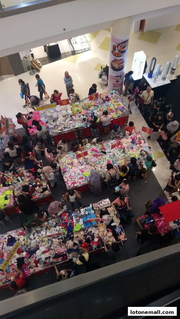 A busy sale event with many people browsing tables filled with bras and other apparel.