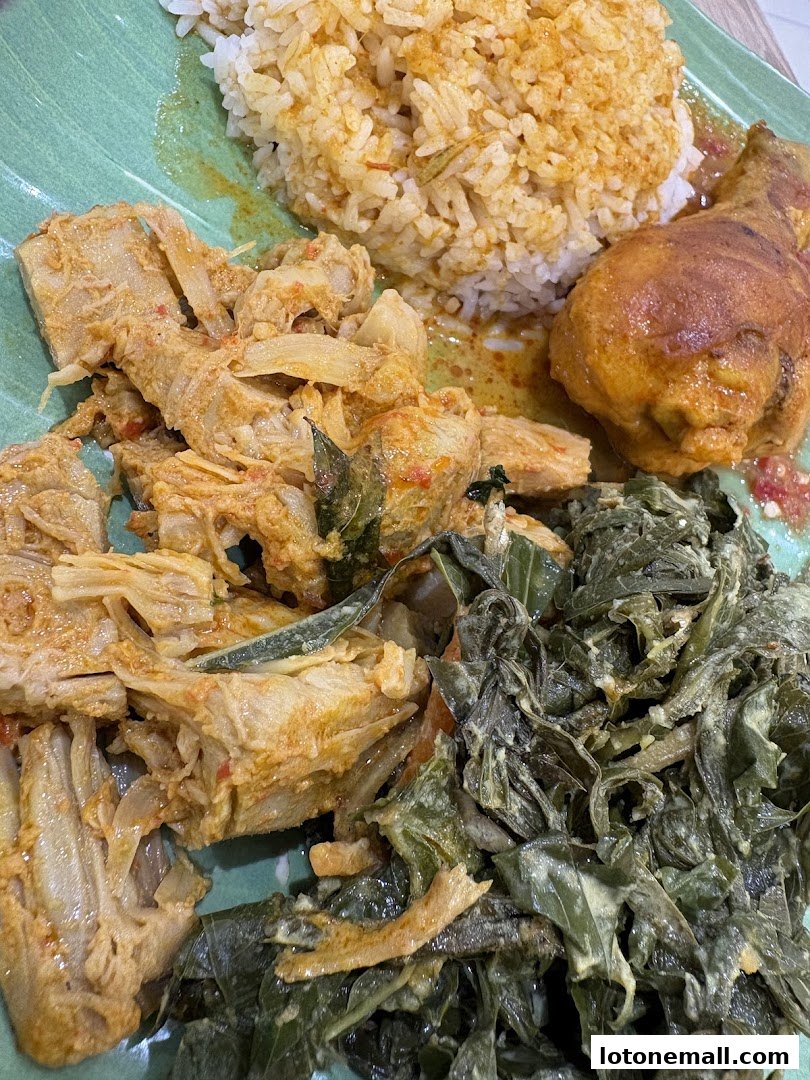 A plate of rice with chicken, jackfruit curry, and leafy greens.