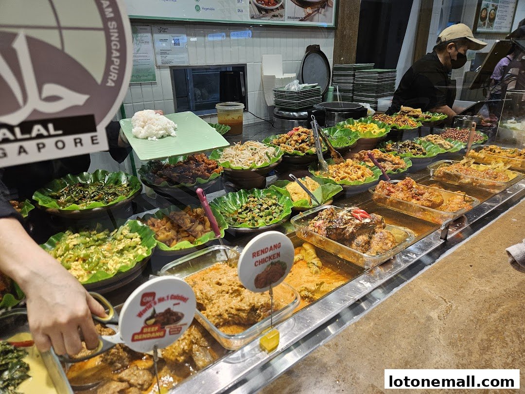 A display of various Indonesian dishes, including beef rendang and chicken, ready to be served.