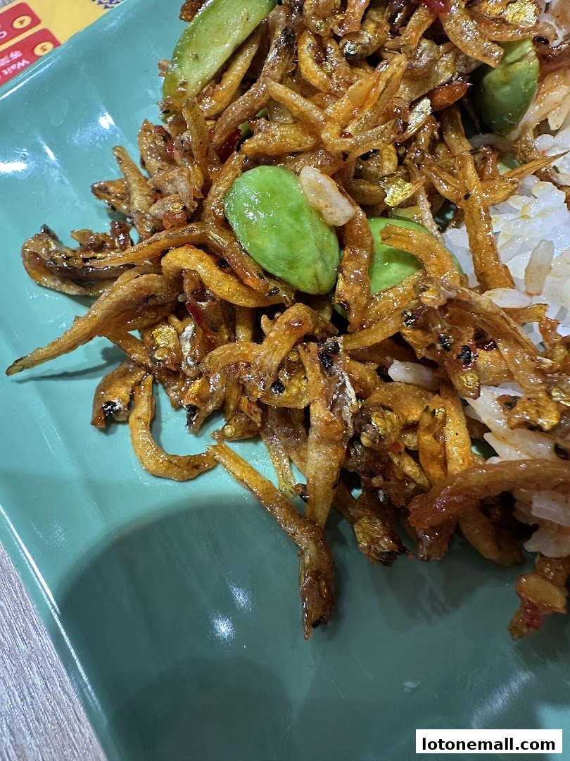 A close-up of a delicious dish featuring fried anchovies and petai beans served with rice.