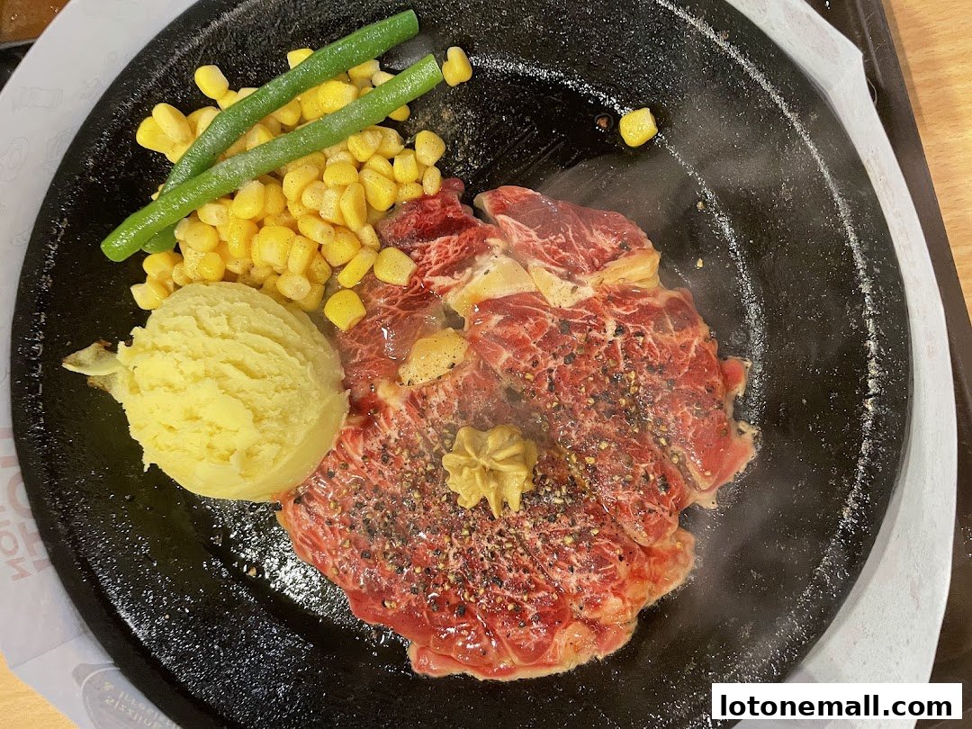 A sizzling steak with mashed potatoes, corn, and green beans on a hot plate.