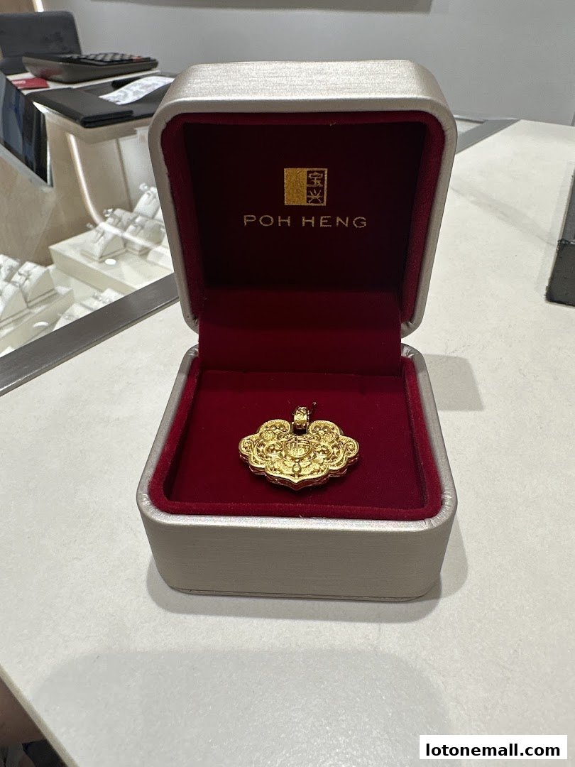 A gold pendant in a Poh Heng Jewellery box, showcasing intricate design.