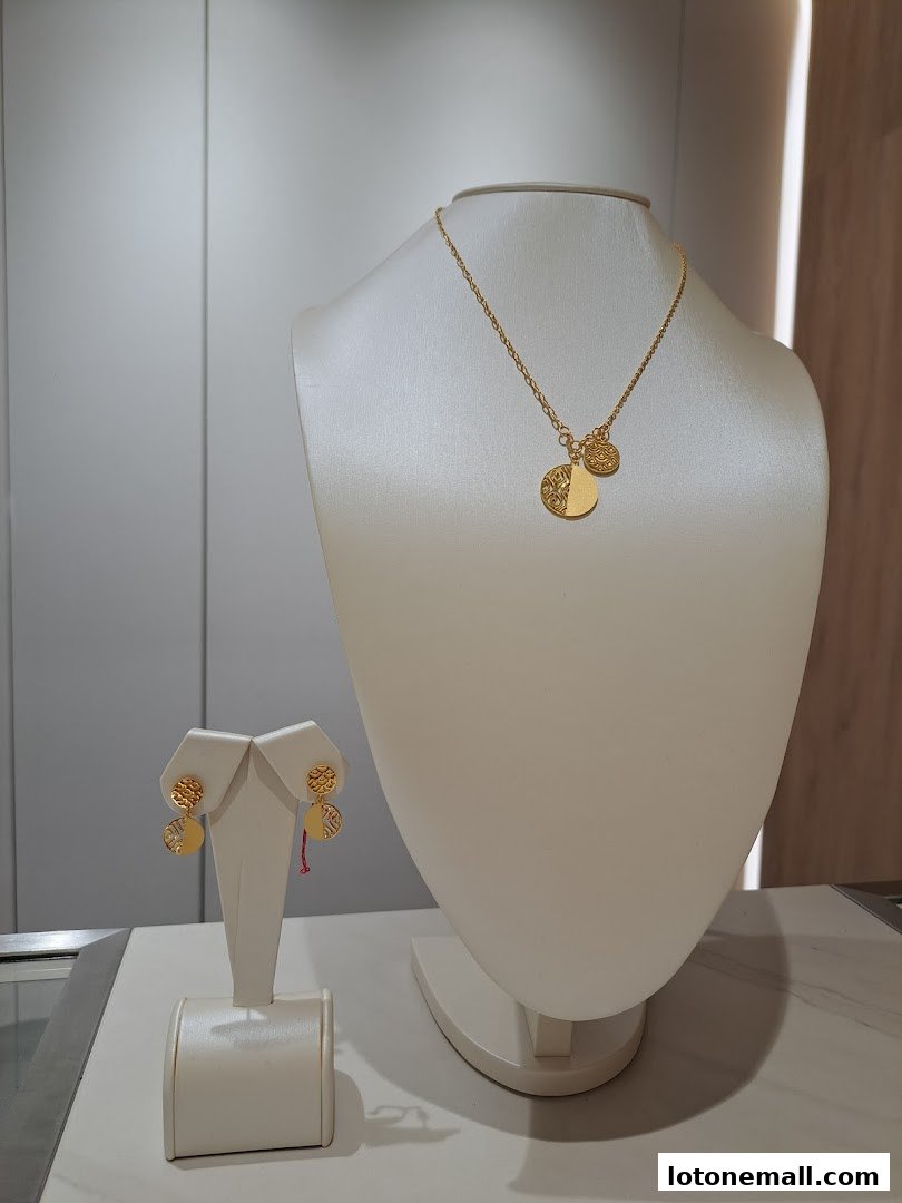 A gold necklace and matching earrings displayed on white jewelry busts.