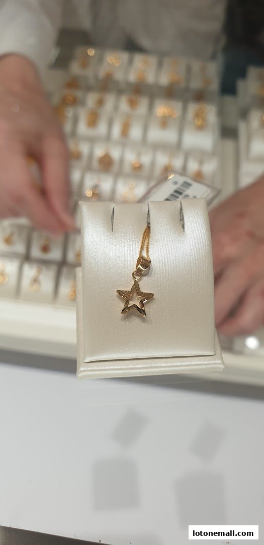 A close-up of a gold star pendant displayed on a white stand at Poh Heng Jewellery.