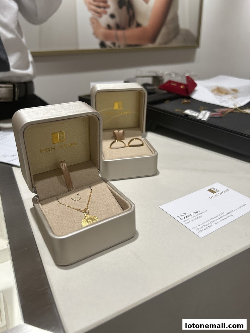Poh Heng Jewellery displays a necklace and wedding rings in their boxes.