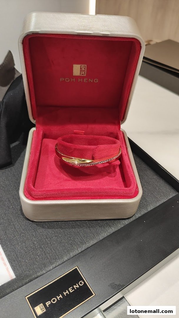 A gold bracelet with small diamonds displayed in a Poh Heng Jewellery box.