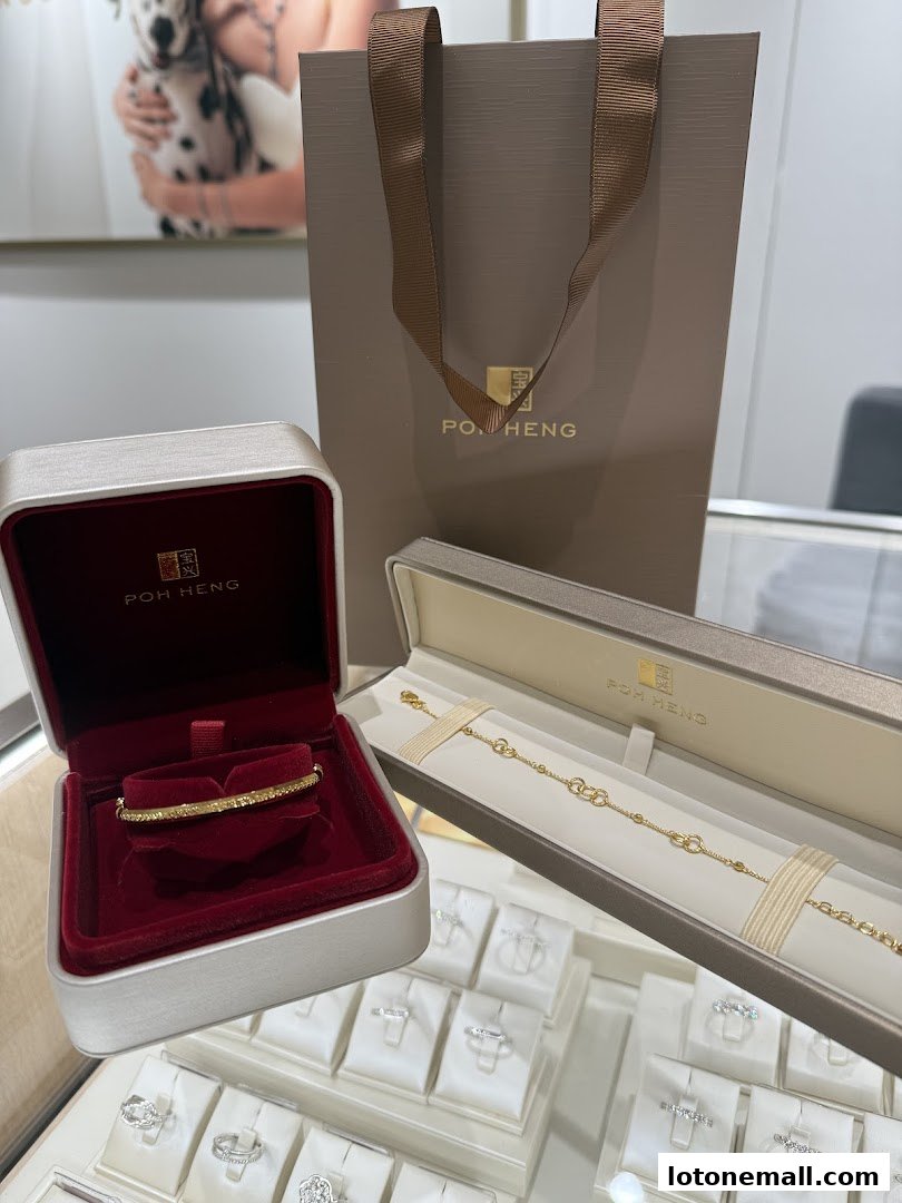 Poh Heng Jewellery displays a gold bracelet and bangle in their branded boxes with a shopping bag.