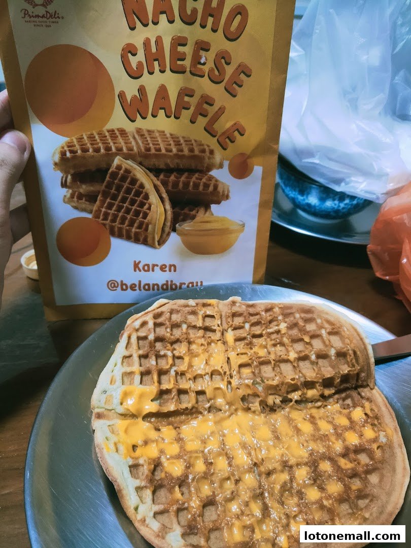 A person holding a package of Nacho Cheese Waffles with a waffle topped with cheese sauce.