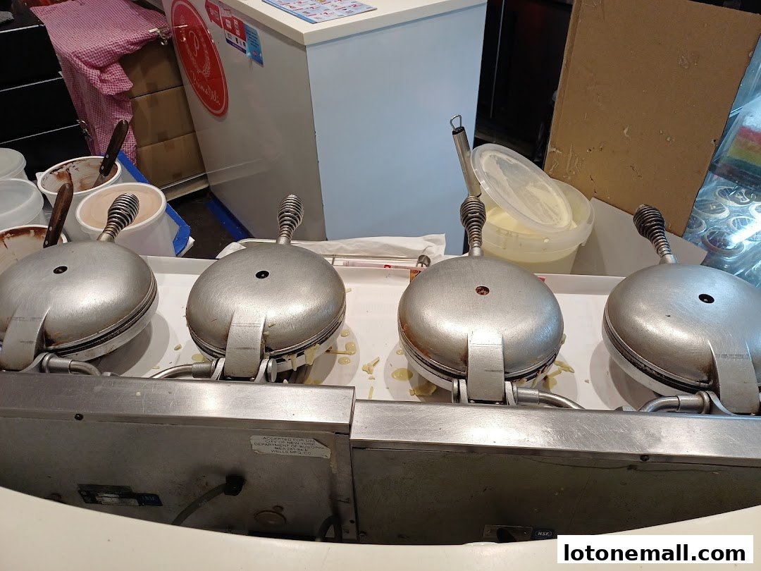 Four waffle makers are lined up, with batter being cooked on them.