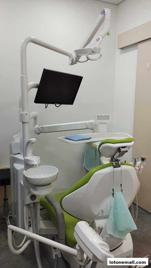 A modern dental chair with a monitor and examination light in a clean clinic.