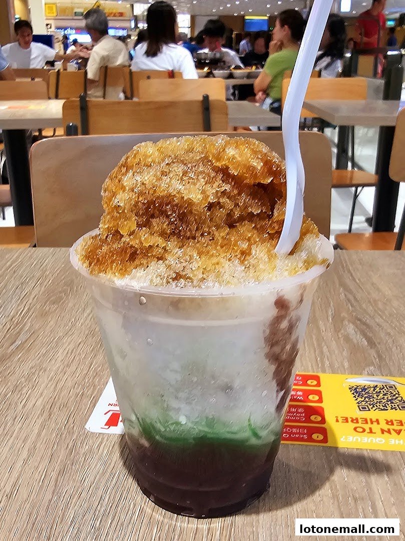 A close-up of a refreshing shaved ice dessert with brown sugar syrup and green jelly.