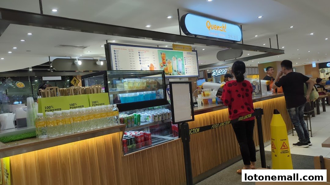 A beverage shop counter with customers ordering drinks and a display of bottled beverages.