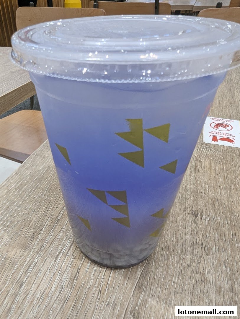 A close-up of a purple beverage in a clear plastic cup with a lid.