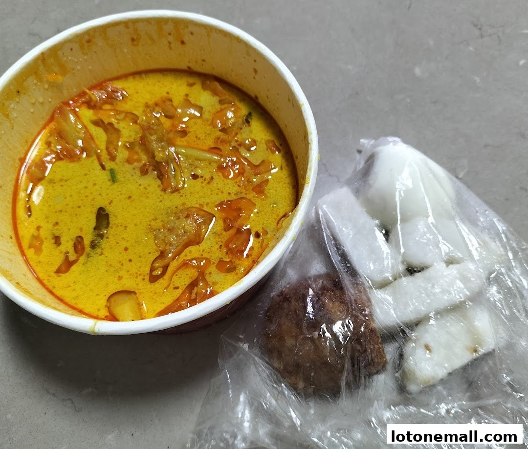 A bowl of yellow curry with meat and vegetables, served with rice cakes and a fried item.