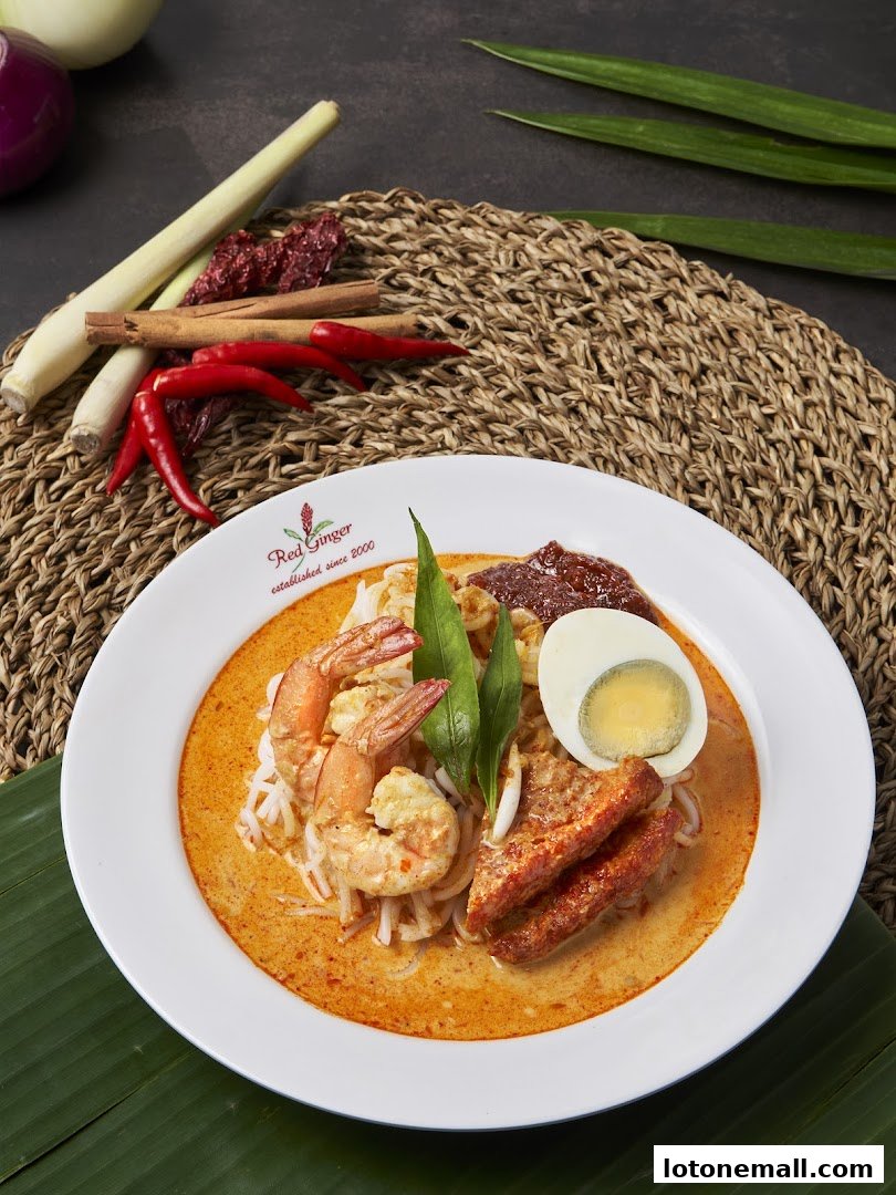A bowl of Laksa with prawns, egg, and fried tofu, garnished with chili and lemongrass.