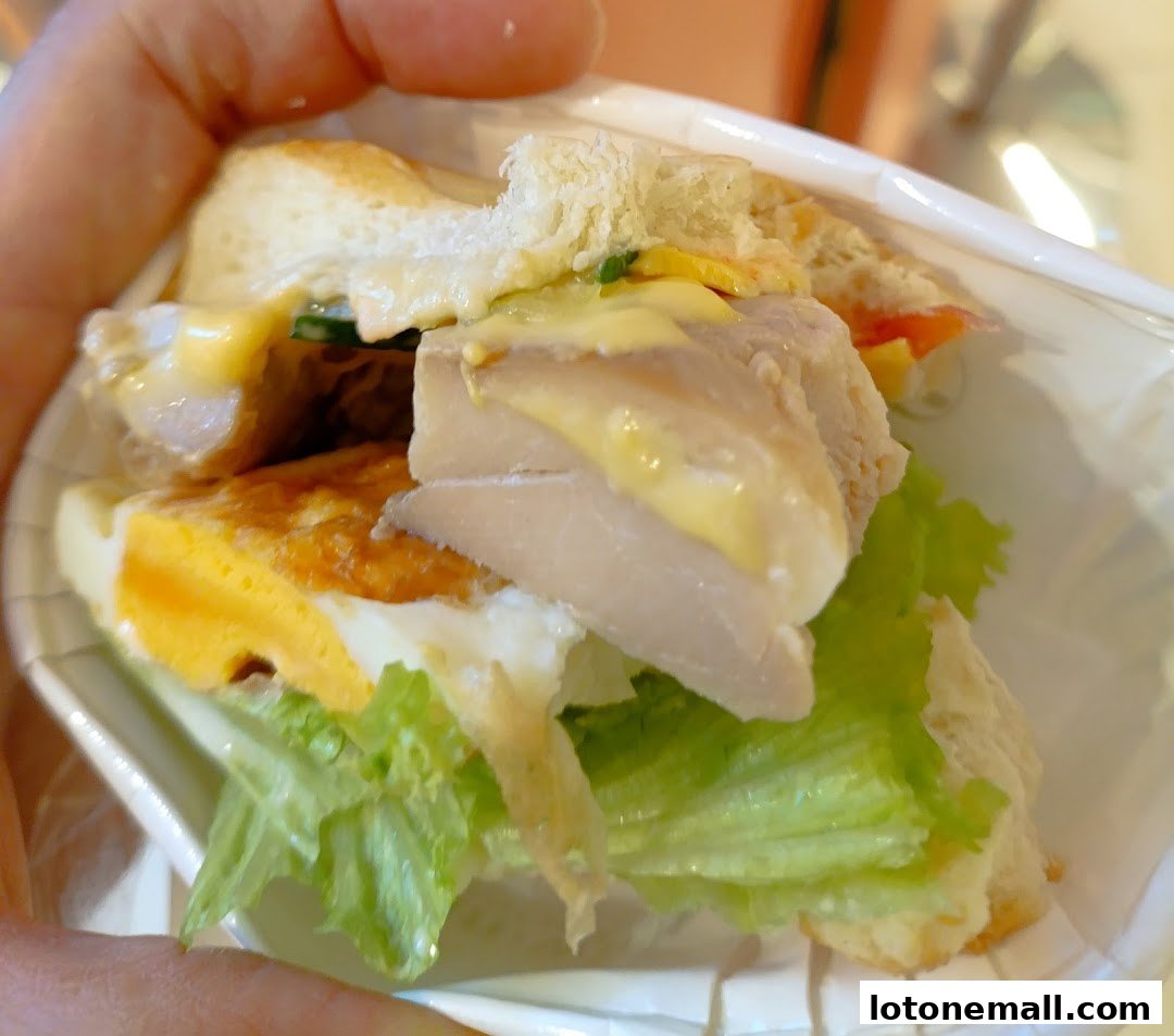 A close-up shot of a delicious sandwich with fish, egg, lettuce, and sauce.
