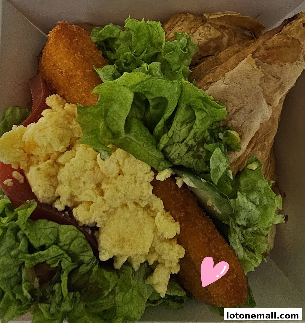 A close-up view of a delicious sandwich with scrambled eggs, lettuce, and fried chicken strips.