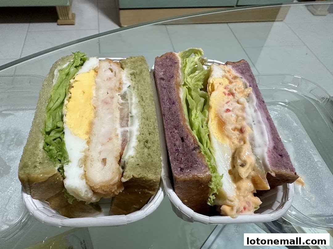 Two delicious sandwiches, one with green bread and fried filling, the other with purple bread and creamy filling.