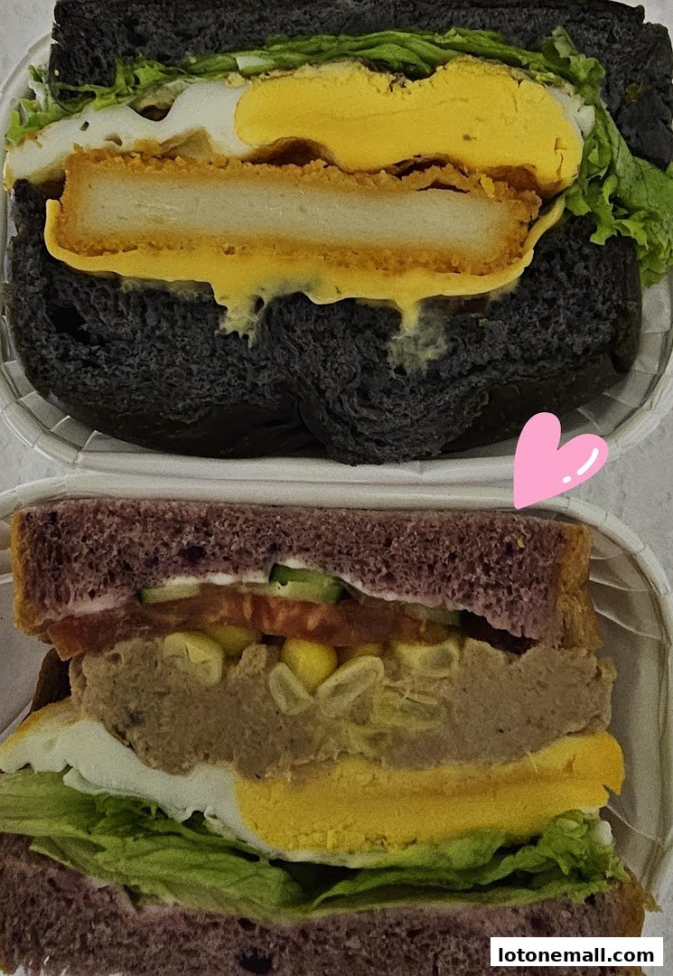 Two delicious and colorful sandwiches, one with black bread and the other with purple bread, are showcased.