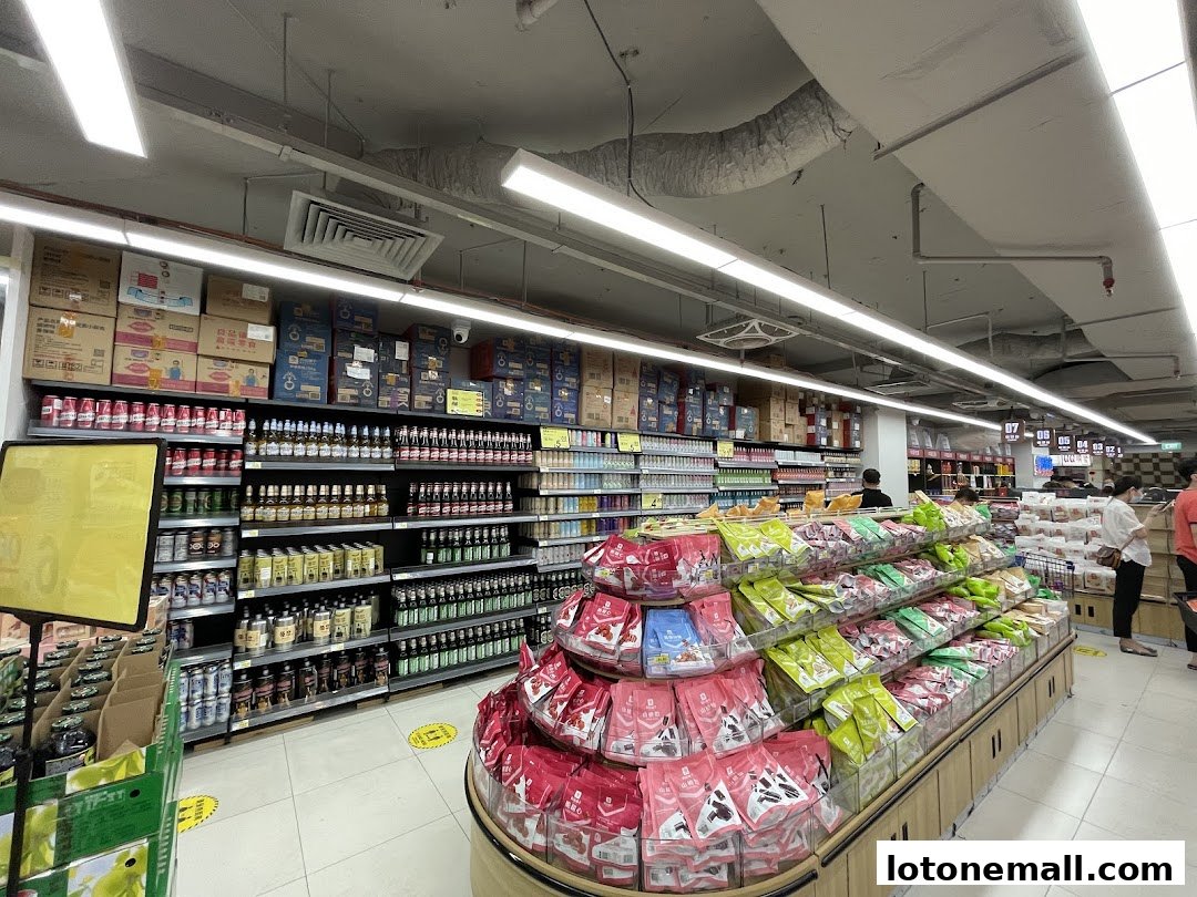 A wide aisle in a supermarket with shelves stocked with drinks and snacks.