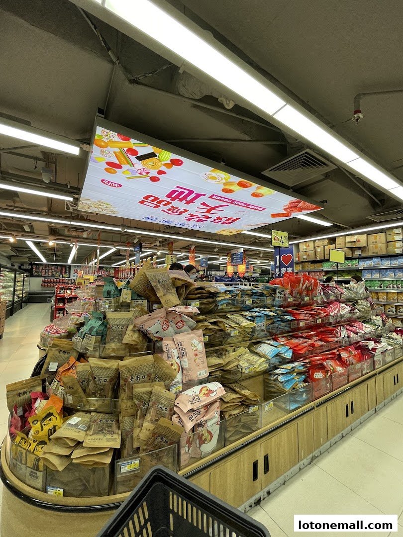 A supermarket aisle filled with various snacks and food items, with a shopping basket in the foreground.