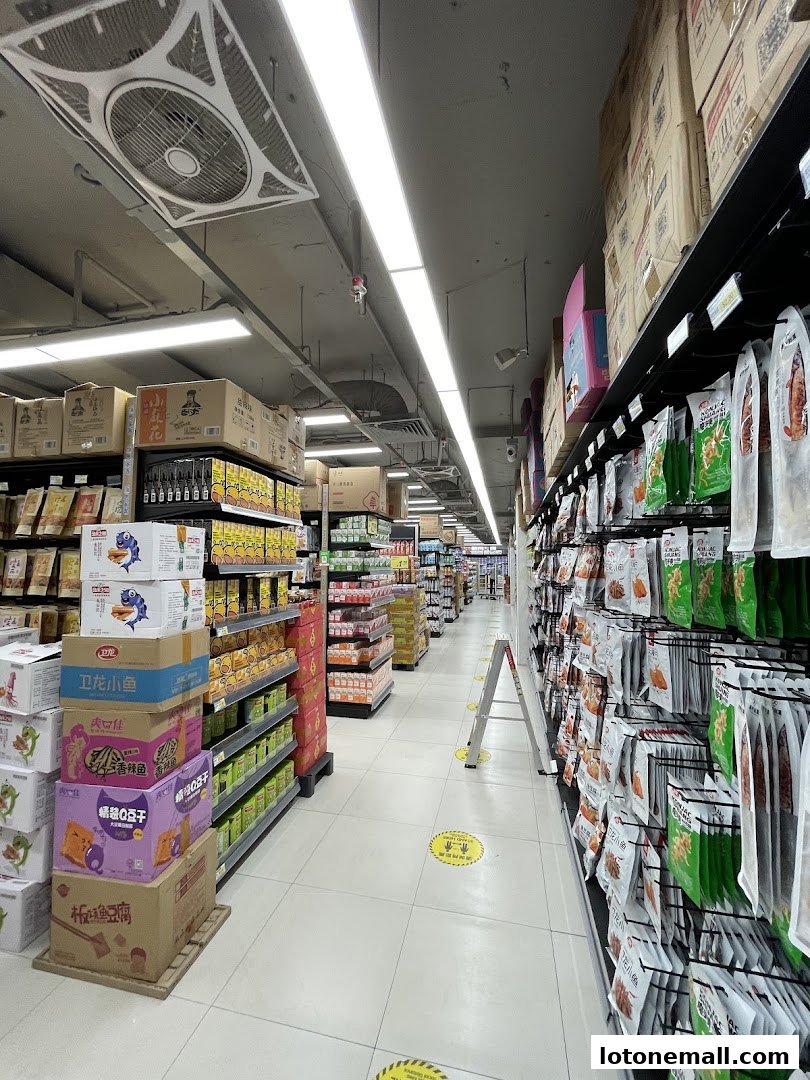 A wide aisle in a supermarket with shelves stocked with various food products and snacks.