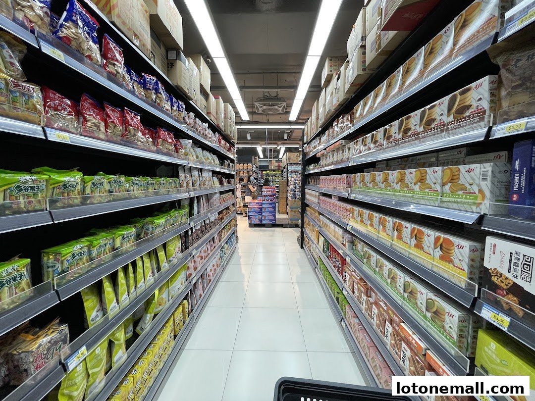 Aisle view of a supermarket with shelves stocked with various snacks and food items.