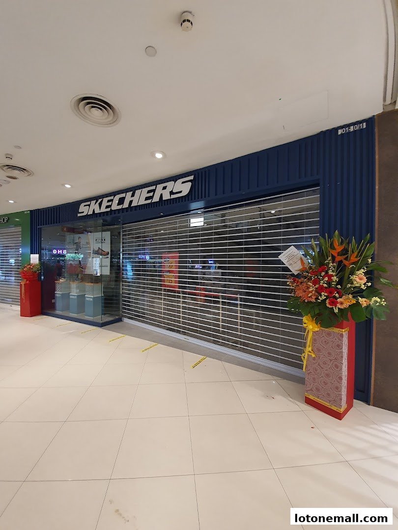 The Skechers store front with its roller shutter down and decorative flowers outside.