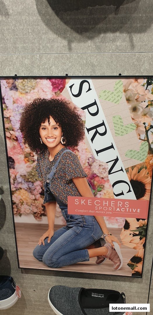 A woman in denim overalls poses with a floral background and Skechers Sportactive branding.