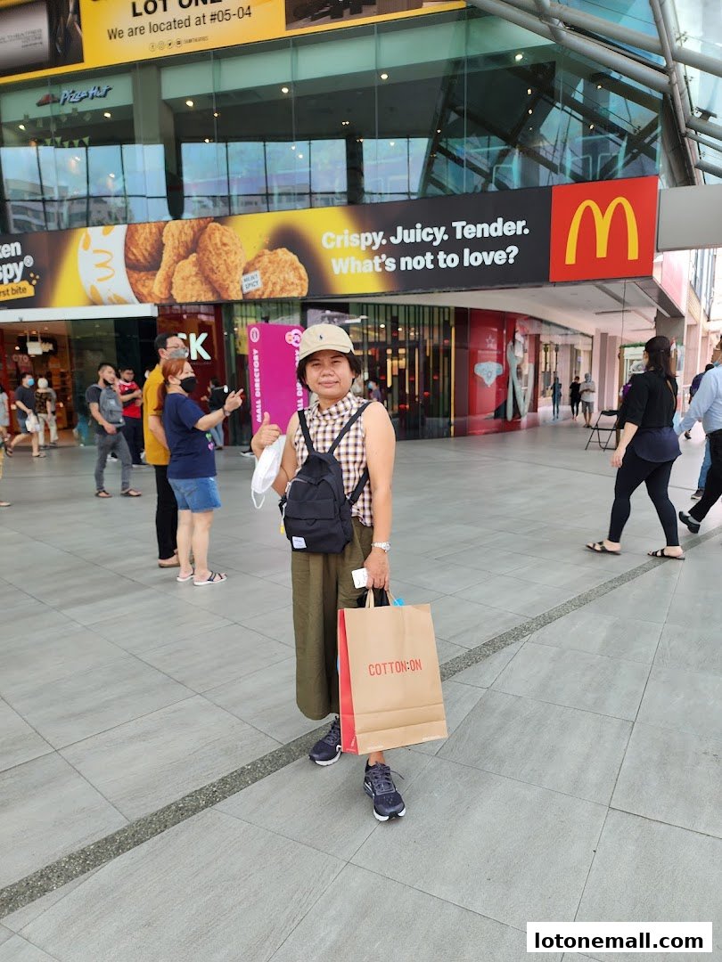 A woman poses with shopping bags in front of a McDonald's advertisement.
