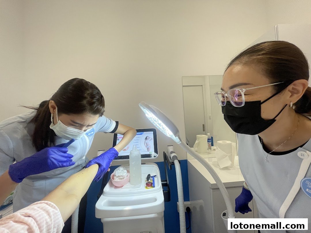 Two aestheticians performing a hair removal treatment on a client's arm.