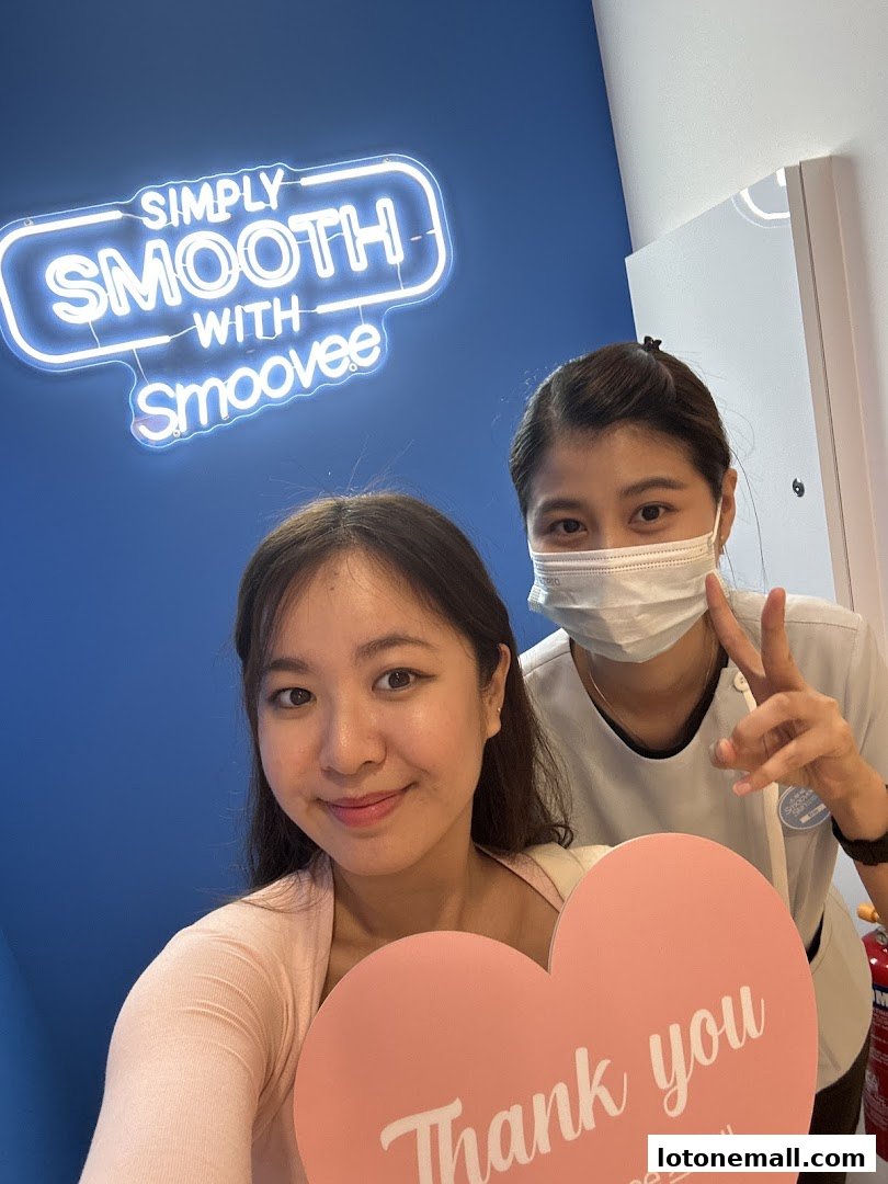 A smiling customer and a staff member pose for a selfie with a 'Thank You' sign.