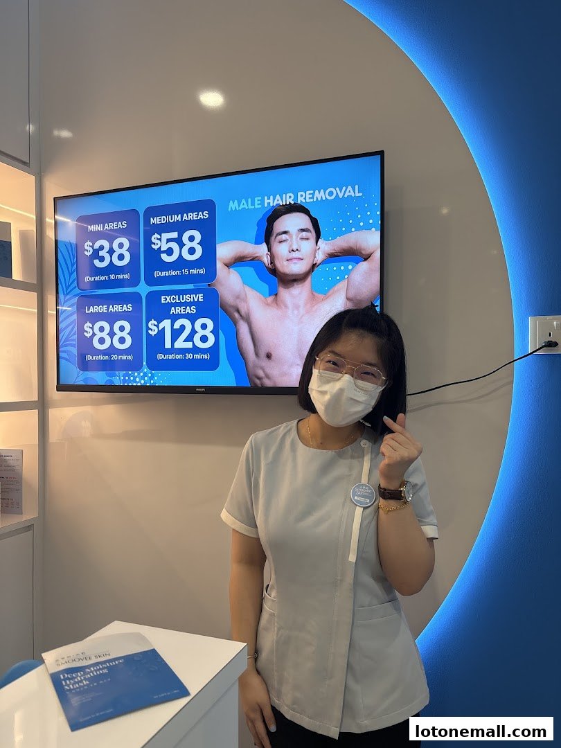 A staff member at Smoovee Skin Korean Hair Removal poses in front of a screen displaying male hair removal prices.